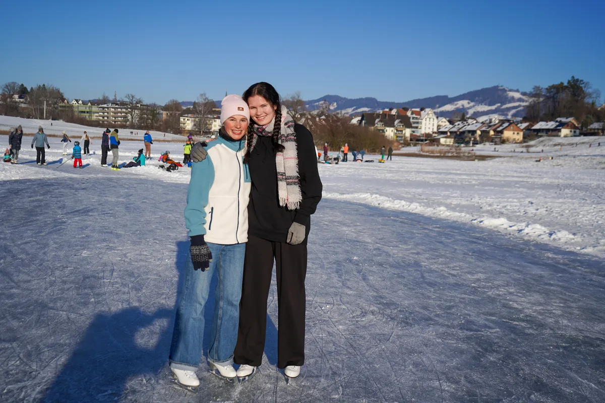 Man sieht zwei junge Frauen auf einem Eisfeld. 